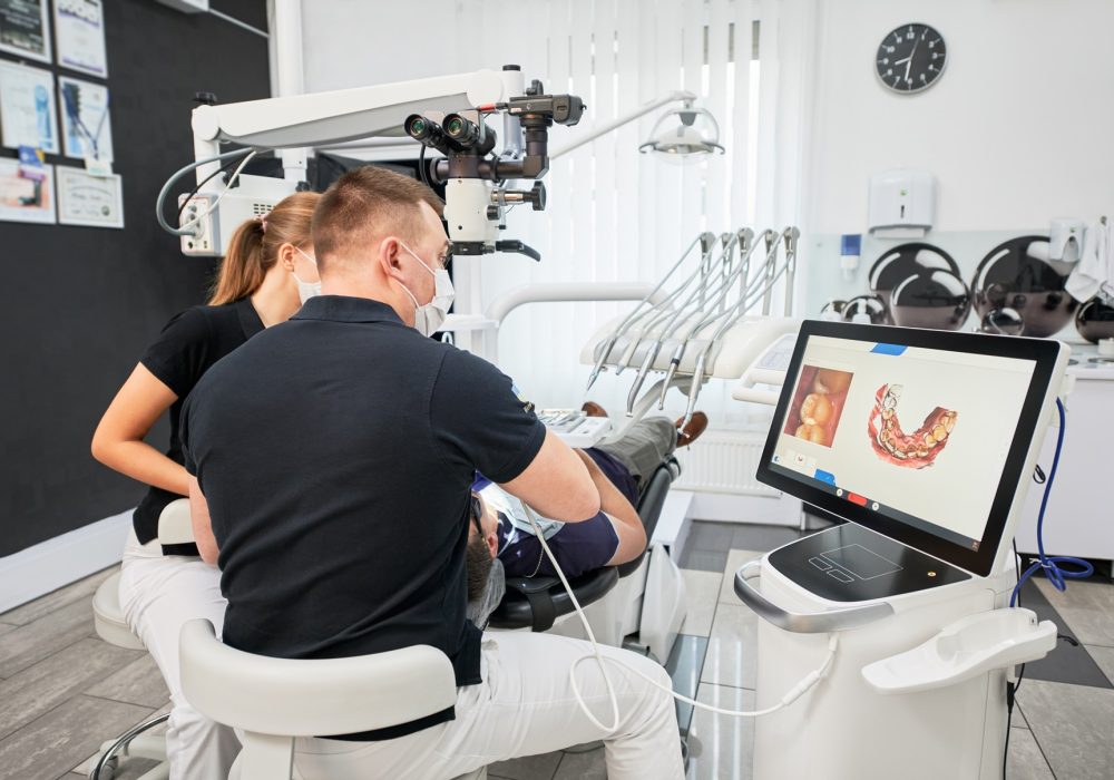 Dentist scanning patient’s teeth with modern machine for intraoral scanning. Dentist scanning patient's teeth with modern machine for intraoral scanning. Digital print of patient's teeth is on big screen. Modern high precision technologies. Concept of modern dentistry